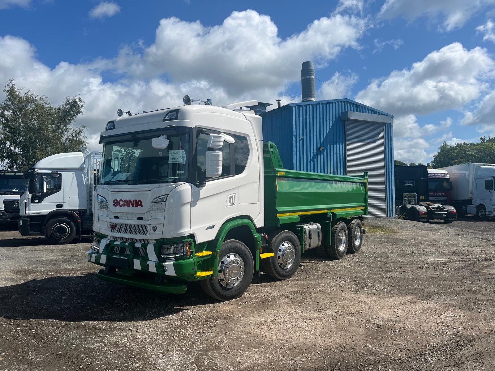 Green and white Scania tipper showing the completed road finish